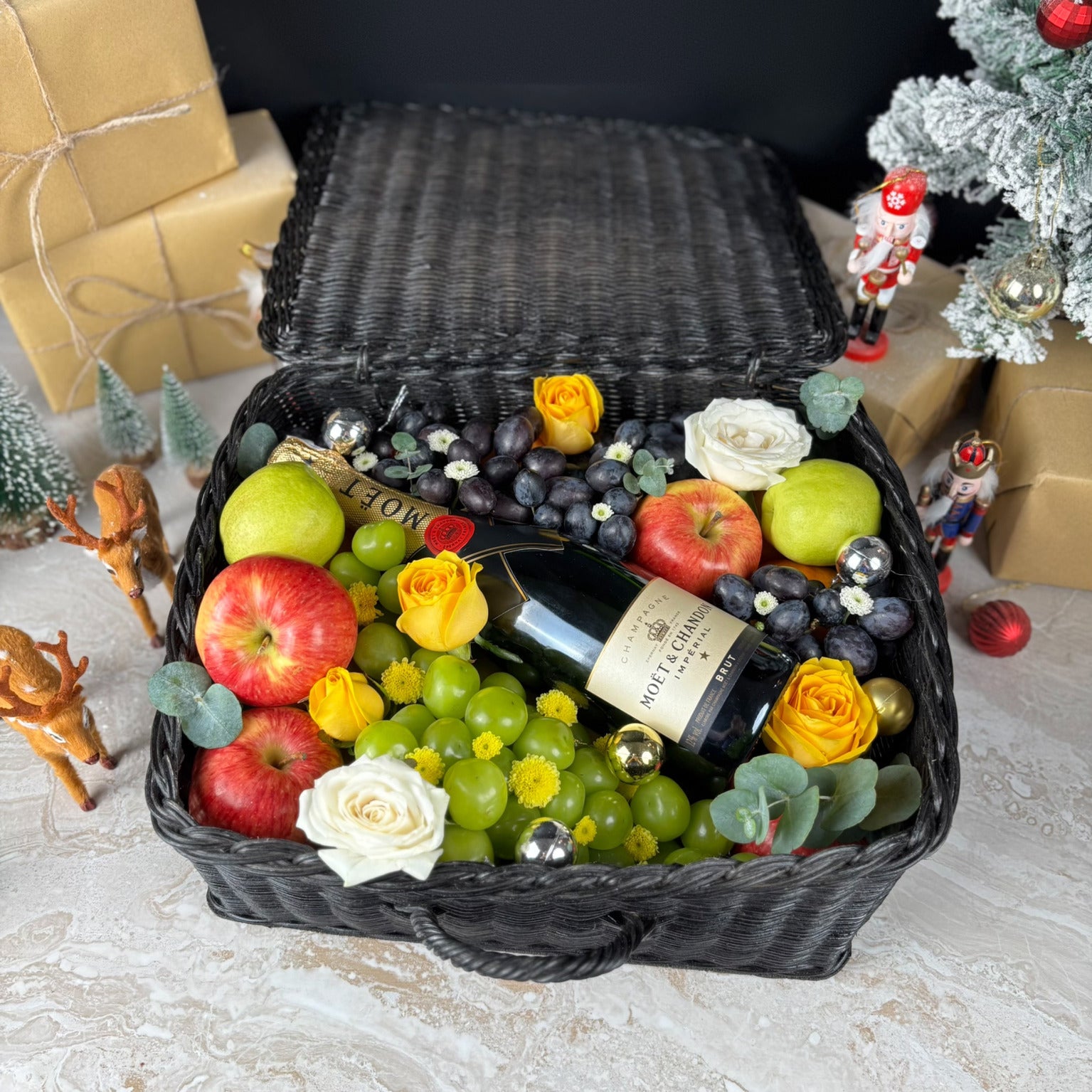 Wine hamper jakarta with fruits, flowers, and a bottle of Moet & Chandon champagne. Fruit basket with moet champagne bottle, apples, grapes, and flowers on a textured surface. Midnight Moët Champagne Hamper | Best Christmas Hamper in Jakarta, Surabaya & Tangerang – Le Bliss Box