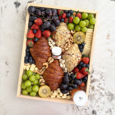 Wooden box filled with fruits, cheeses, and pastries on a marble surface. brunch platter jakarta, brunch platter surabaya, cheese platter jakarta. the best cheese platter and grazing service in jakarta by le bliss platter