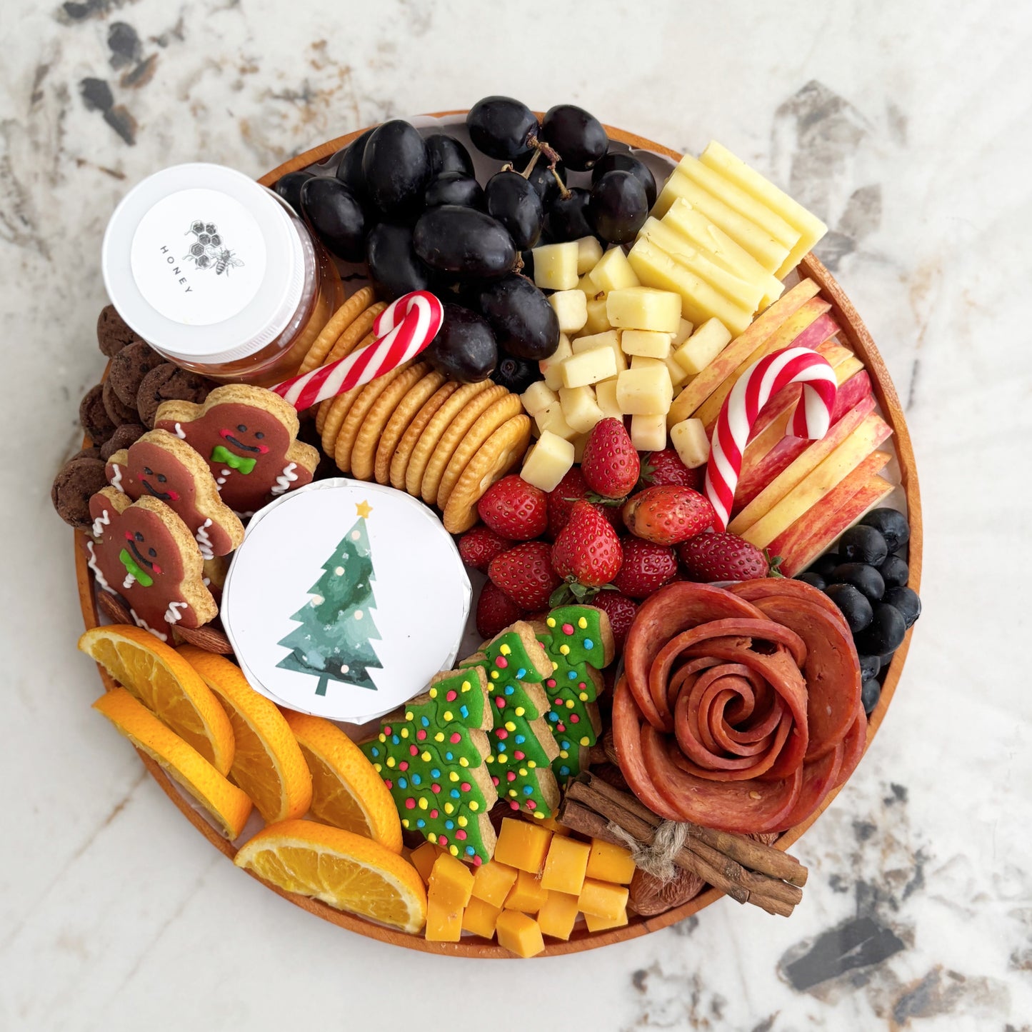 christmas charcuterie board surabaya with fruits, cookies, and a small Christmas tree on a table with festive decorations.  festive charcuterie board with fruits, cheese, and meats on a marble surface. Best Christmas Platter Jakarta & Surabaya – Le Bliss Platter