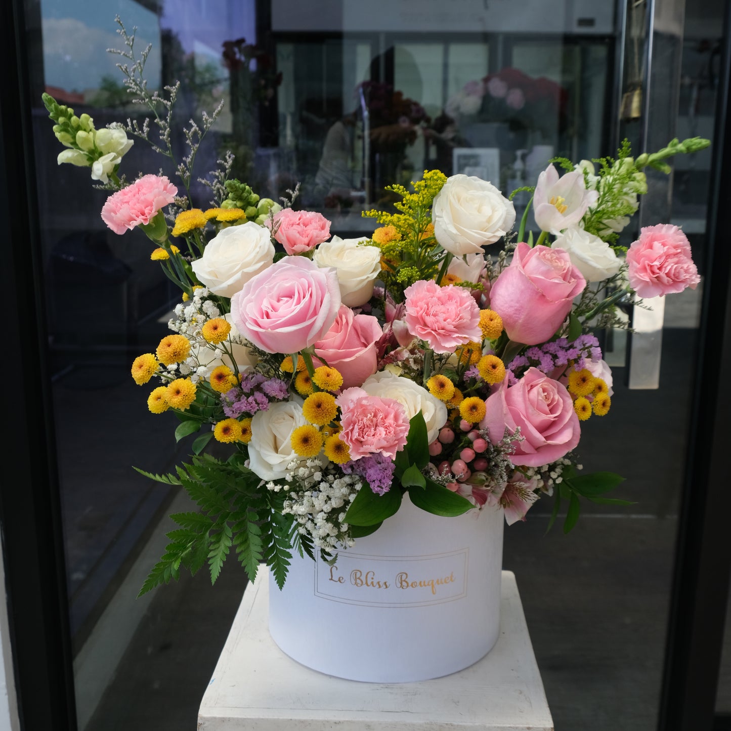 colorful flower arrangement. Bloombox flowers with a white cylindrical container on a gray background. Jakarta florist, tangerang, surabaya, cirebon. toko bunga jakarta