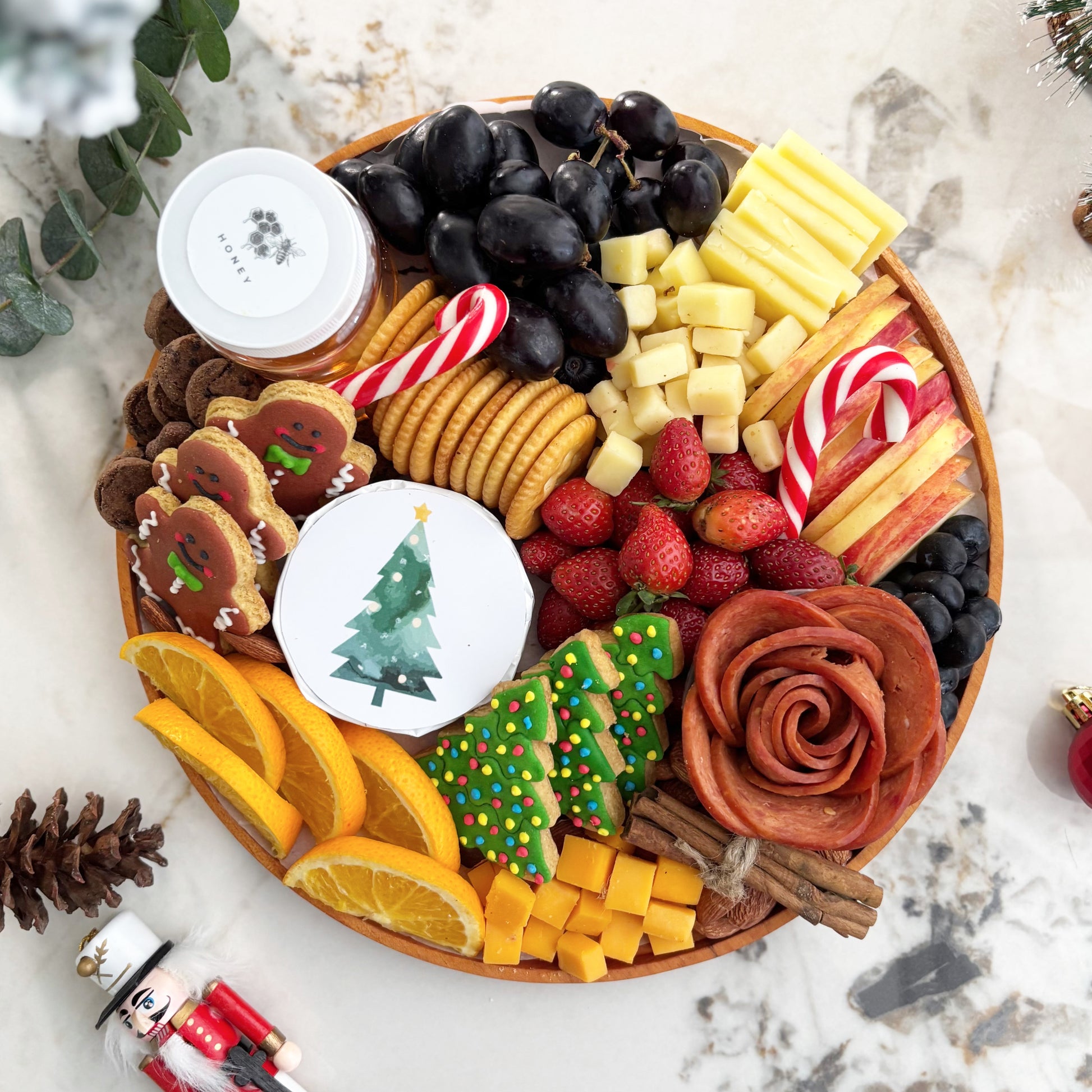  festive charcuterie board with fruits, cheese, and meats on a marble surface. Christmas Round Cheese Platter | Christmas Platter Jakarta & Surabaya – Le Bliss Platter