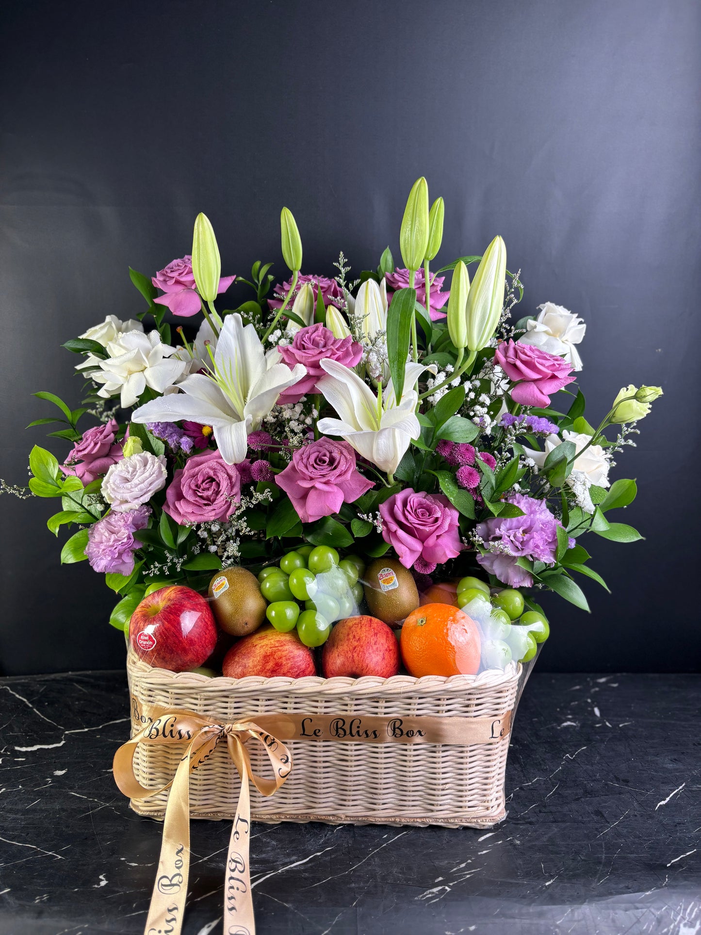 fruit hamper of purple flowers and fruits on a dark surface with a black background. Fruit hamper jakarta, cirebon, surabaya, tangerang. by le bliss box, parcel buah premium terbaik