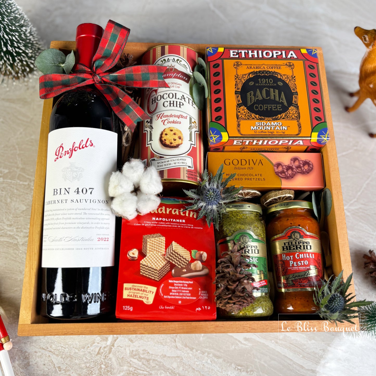 hamper basket with wine, cookies, coffee, and snacks on a textured surface. wine bin 407 penfolds, bacha coffee and other. gourmet hamper jakarta, surabaya. parcel natal jakarta, parcel natal surabaya