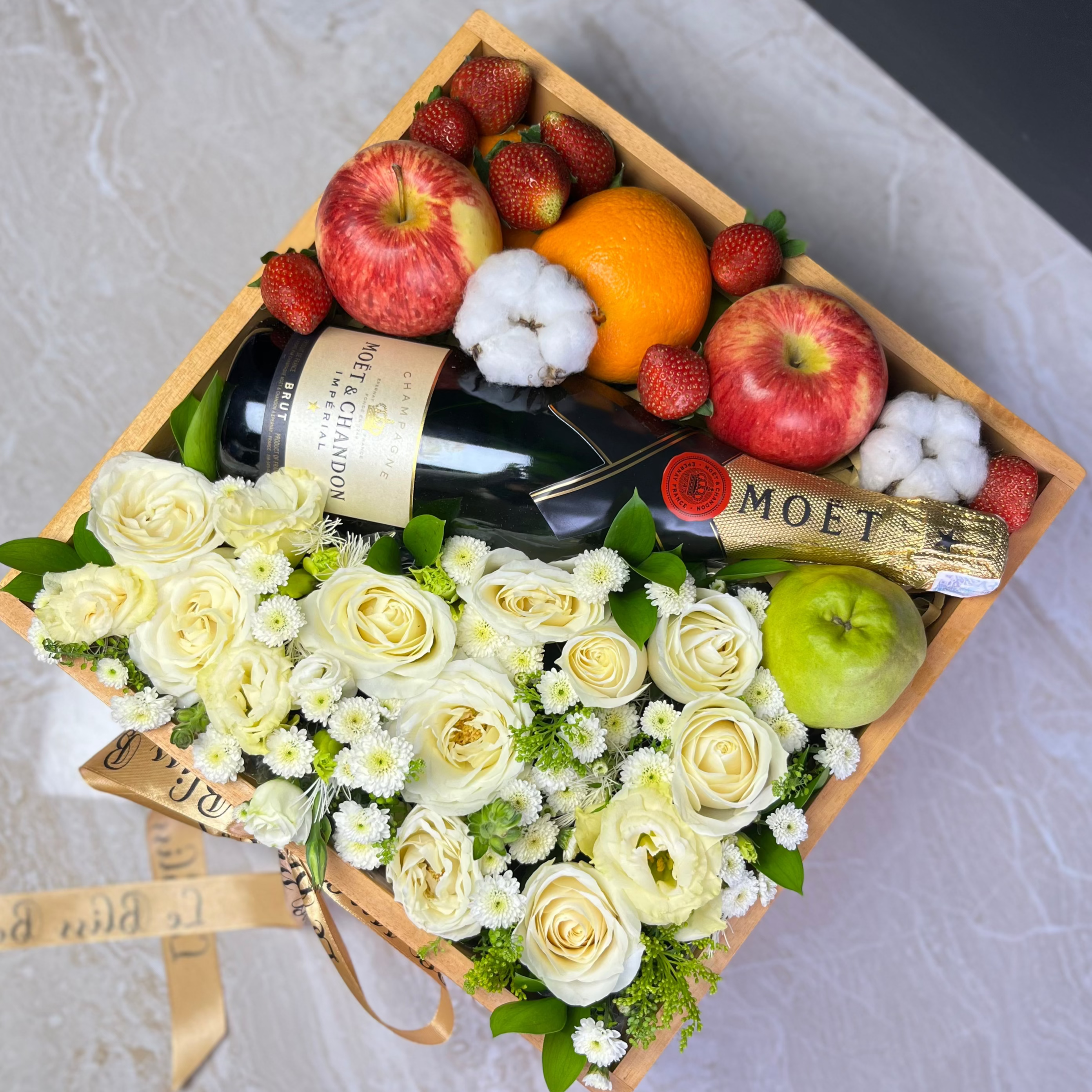 moet hamper jakarta, with flowers, fruits, and a bottle of Moët champagne on a marble surface. Wine hamper jakarta, wine hamper surabaya, tangerang, depok, bekasi, bogor by le bliss