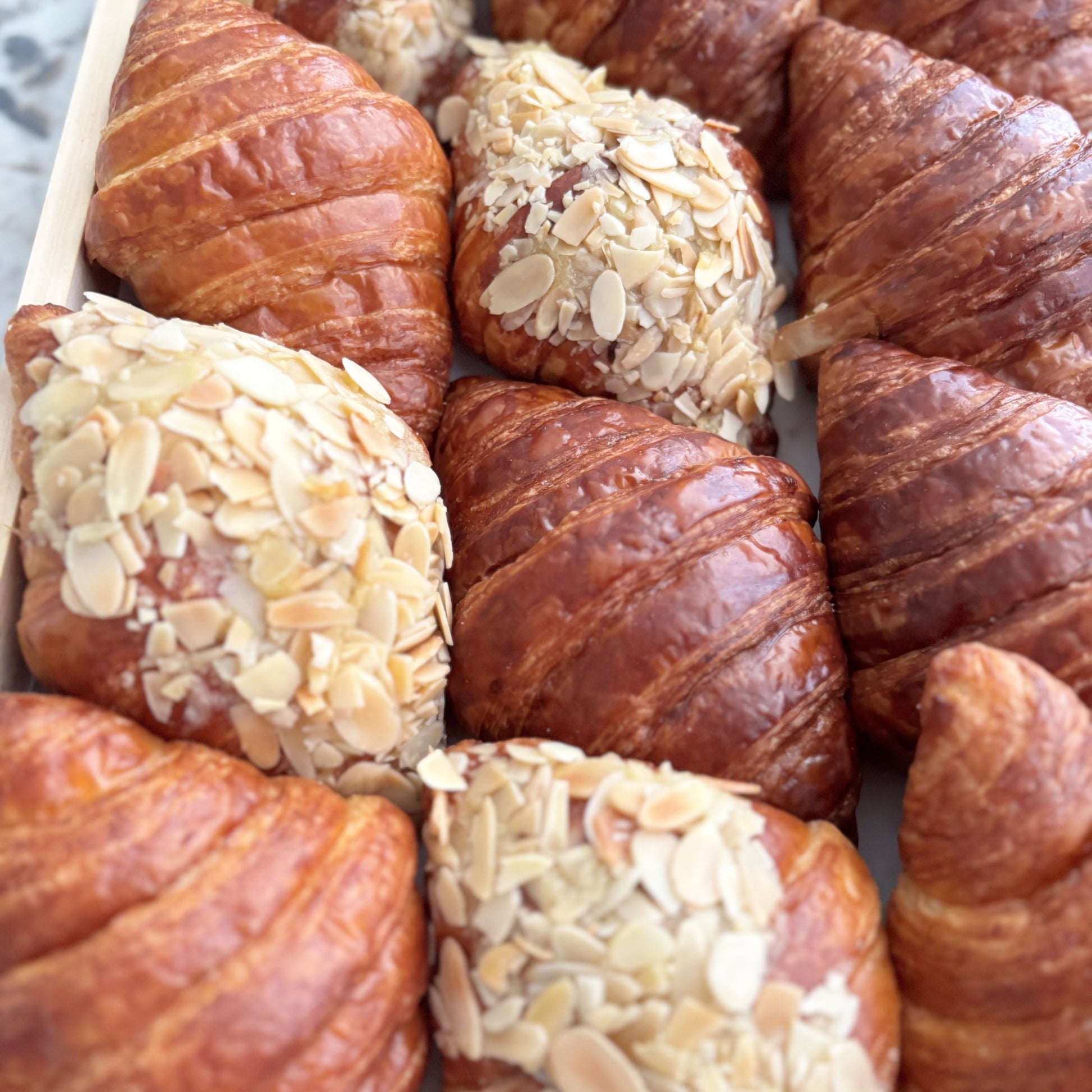 Assorted pastries including croissants and buns with seeds on a white plate.