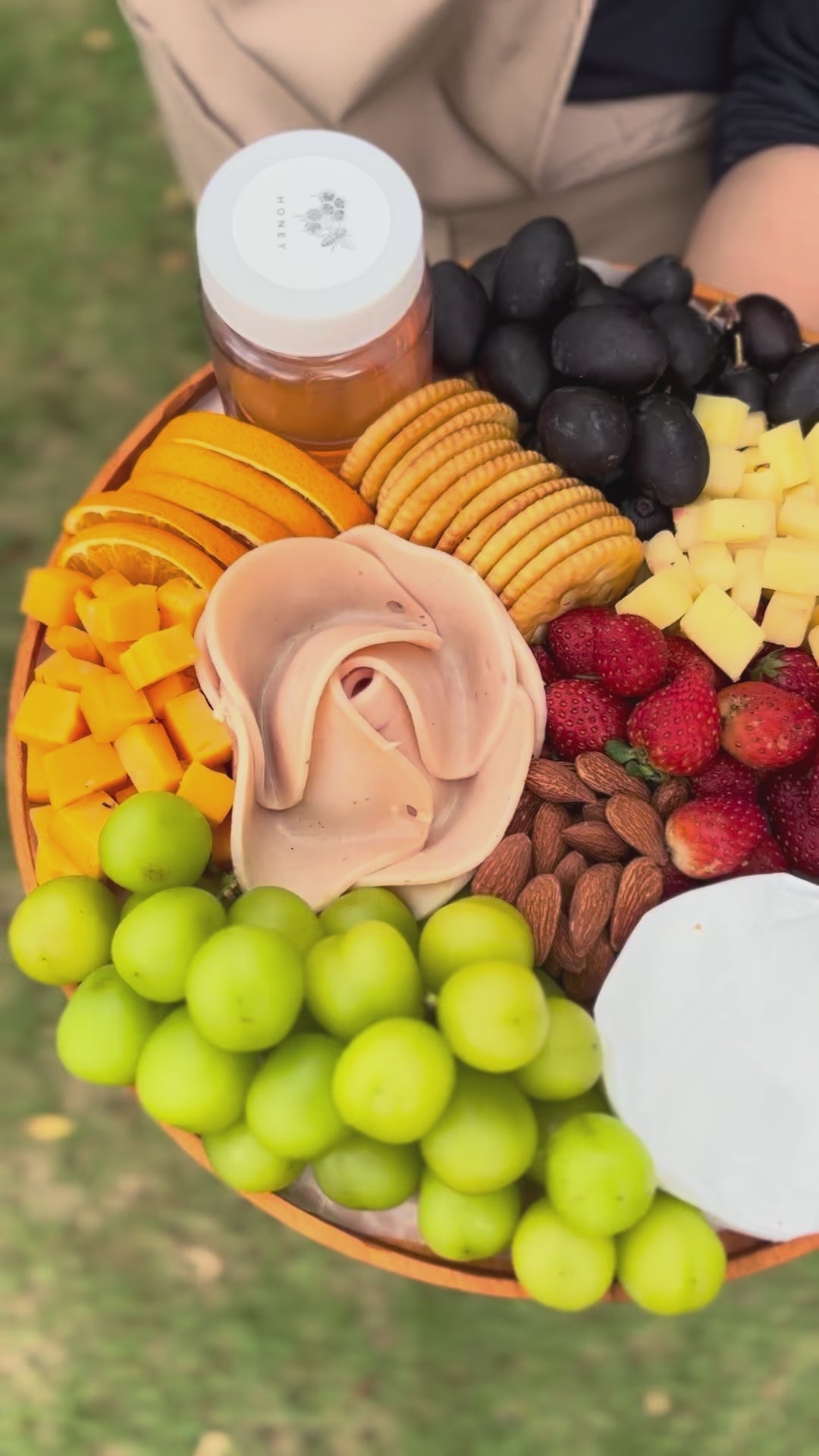 chicken salami cheese platter. Assorted fruits, cheeses, and nuts on a platter with a blurred green background. best cheese platter in jakarta, surabaya. 