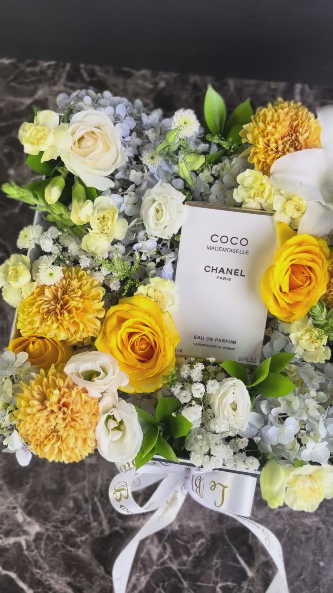 Floral arrangement with a Chanel perfume bottle at the center on a marble surface. Perfume hamper jakarta, surabaya by le bliss bouquet