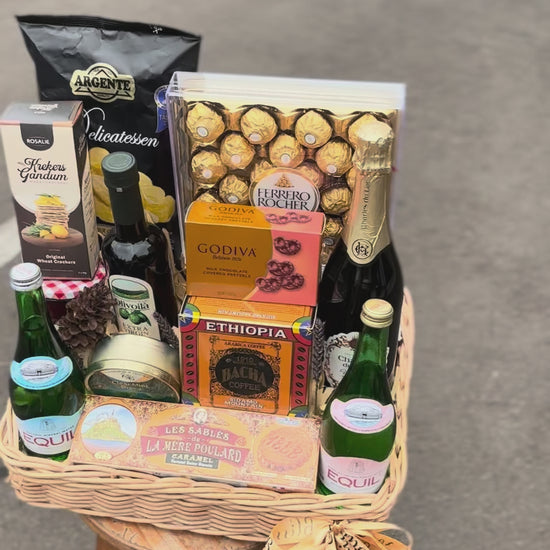 Gift basket with snacks, drinks, and chocolates on a dark surface. hamper jakarta, hamper surabaya, gourmet hamper jakarta