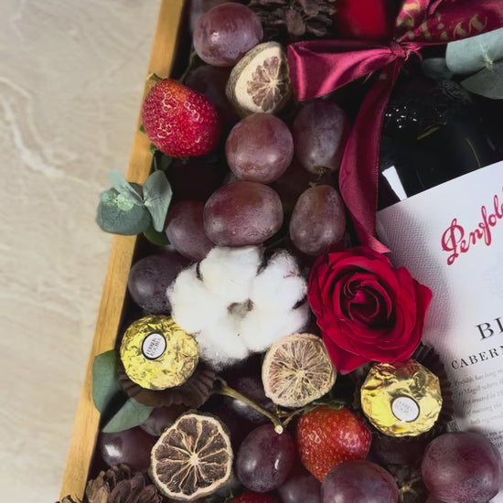 Wine bottle in a decorative box with fruits and flowers on a marble surface. Penfolds Wine Hamper Jakarta by Le Bliss Box