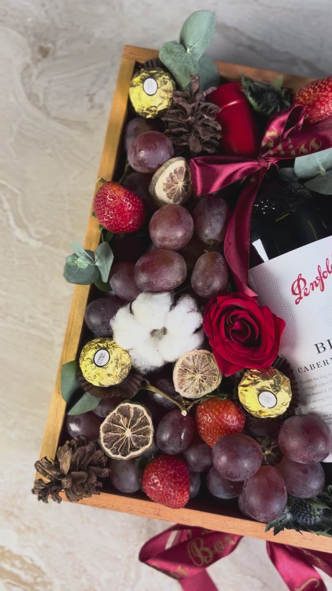 Wine bottle in a decorative box with fruits and flowers on a marble surface. Penfolds Wine Hamper Jakarta by Le Bliss Box