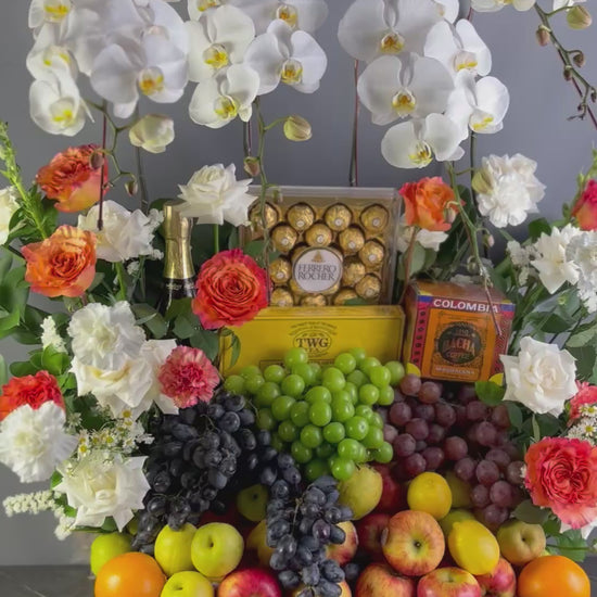 Fruit and flower arrangement with chocolates on a wooden stand against a gray background. luxury fruit hamper jakarta with wine. wine hamper surabaya & jakarta