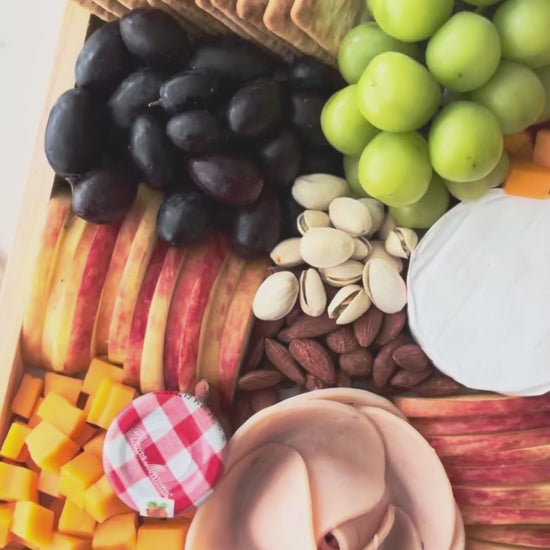 Assorted fruits, cheeses, and crackers on a wooden tray with a marble background, chicken salami, chicken pastrami, cheese platter jakarta, cheese platter surabaya