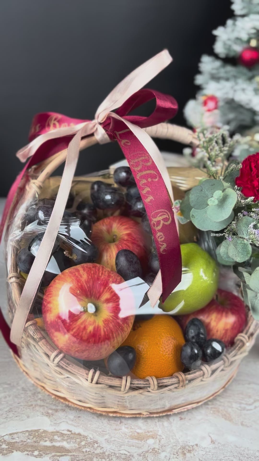 Fruit basket with flowers and a red ribbon on a festive background. Christmas Blossom Fruit Parcel | Best Christmas Hamper Jakarta, Tangerang, Cirebon & Surabaya – Le Bliss Bouquet