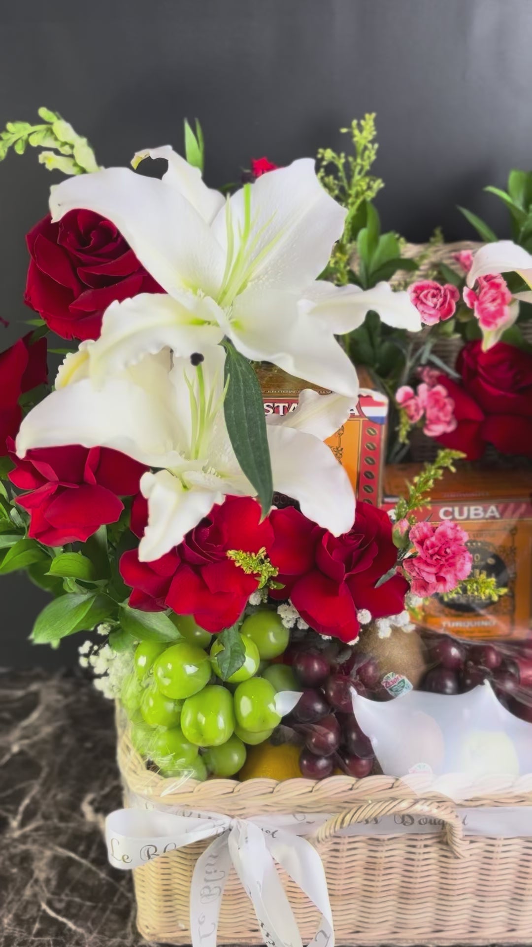 Floral arrangement in a basket with fruits and a box of bacha coffee on a dark surface, bacha coffee hamper surabaya, jakarta, tangerang. cirebon
