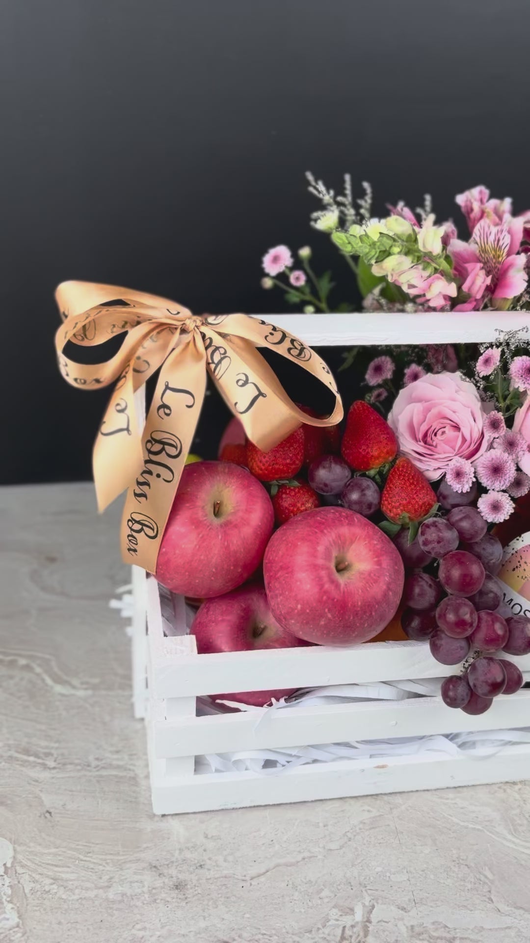 parcel buah dengan bunga dan wine. Gift basket with fruits, flowers, and a bottle of wine on a dark background. sababay wine hamper surabaya, jakarta, tangerang. fruit hamper with wine