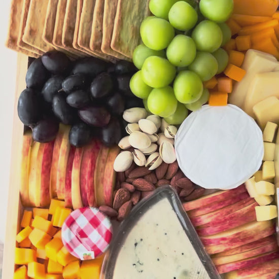 Assorted fruits, cheeses, and crackers on a wooden board with a bottle of champagne. Bottega Wine Cheese Platter | Best Wine & Cheese Platter in Jakarta & Surabaya – Le Bliss Platter