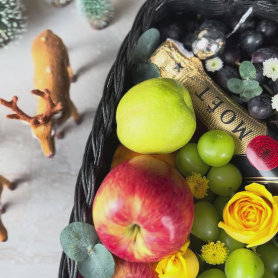 Fruit basket with moet champagne bottle, apples, grapes, and flowers on a textured surface. Midnight Moët Champagne Hamper | Best Christmas Hamper in Jakarta, Surabaya & Tangerang – Le Bliss Box