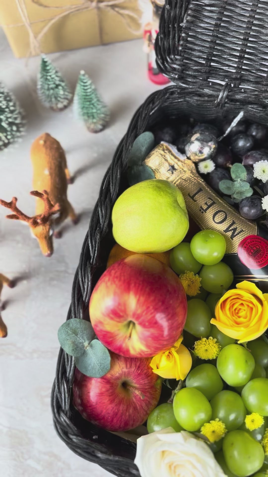 Fruit basket with moet champagne bottle, apples, grapes, and flowers on a textured surface. Midnight Moët Champagne Hamper | Best Christmas Hamper in Jakarta, Surabaya & Tangerang – Le Bliss Box